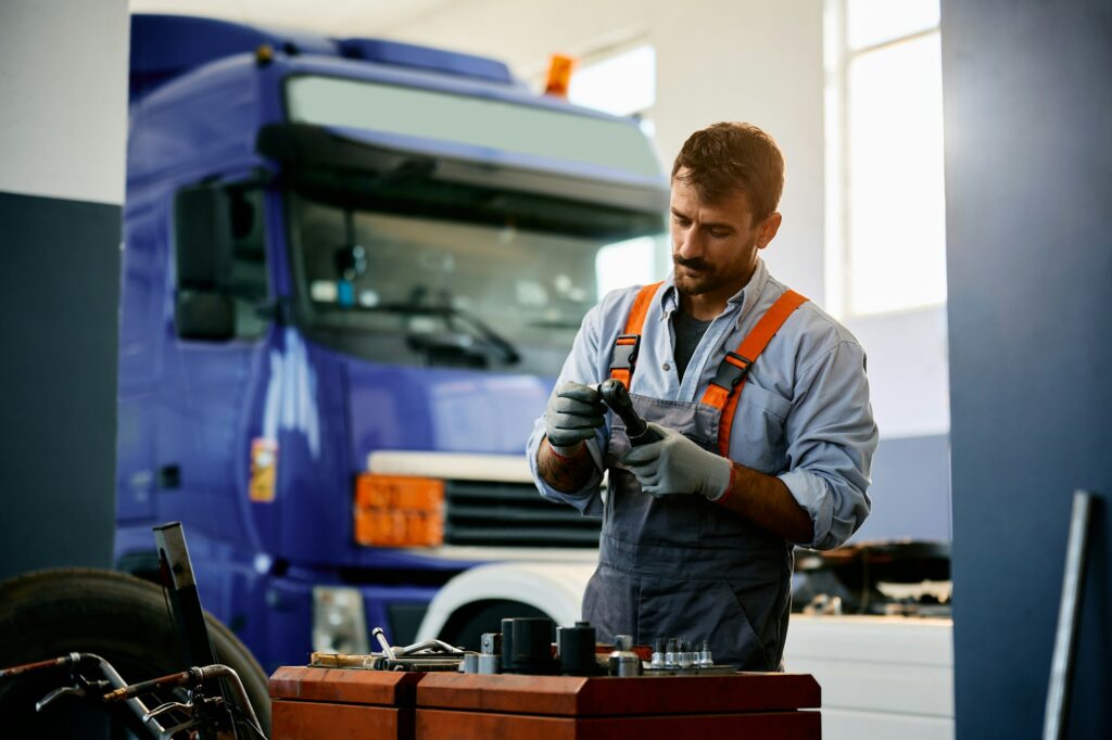 Mid adult truck mechanic working in a garage.